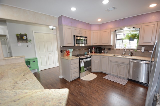 kitchen featuring appliances with stainless steel finishes, visible vents, a sink, and light stone countertops