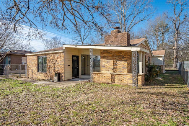 back of house with a yard, stone siding, fence, and a chimney