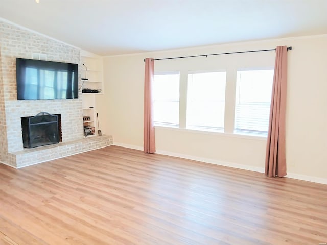 unfurnished living room featuring wood finished floors, a brick fireplace, lofted ceiling, and baseboards