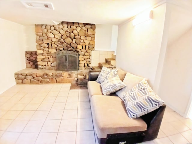 tiled living area with a stone fireplace and visible vents