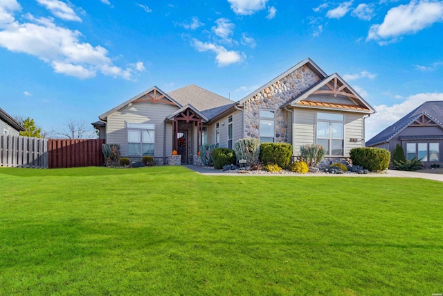 craftsman-style house featuring stone siding, fence, and a front lawn