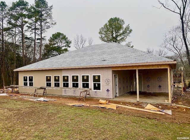 back of house featuring a lawn and stucco siding