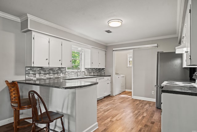 1204 Marion Anderson Rd, Hot Springs, AR 71913 - kitchen featuring ornamental molding, a peninsula, washing machine and dryer, white cabinets, and backsplash