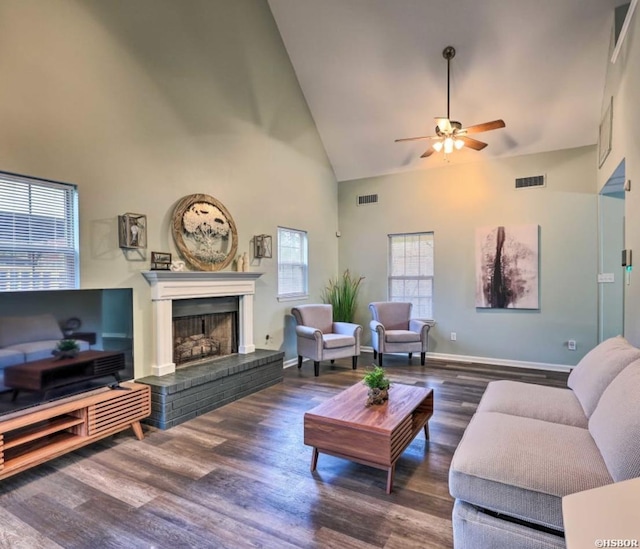 living room featuring high vaulted ceiling, a brick fireplace, visible vents, and dark wood finished floors