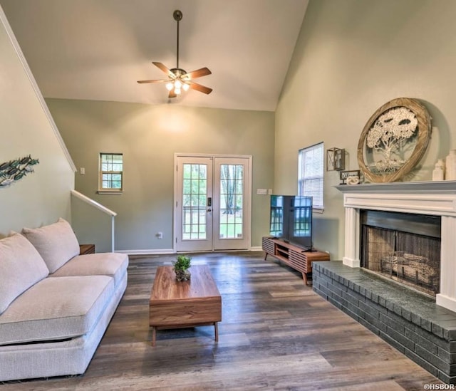 living room with dark wood-type flooring, a brick fireplace, high vaulted ceiling, and baseboards