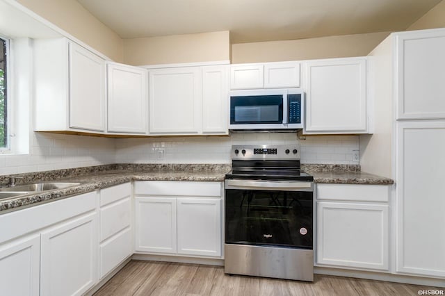 kitchen featuring stainless steel range with electric stovetop, white cabinetry, and backsplash