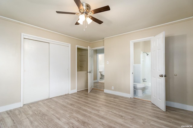 unfurnished bedroom with ornamental molding, a closet, connected bathroom, and light wood-style flooring