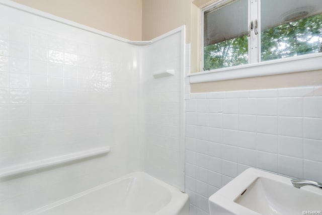 bathroom featuring  shower combination and tile walls