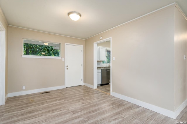 unfurnished room featuring light wood finished floors, baseboards, visible vents, and crown molding