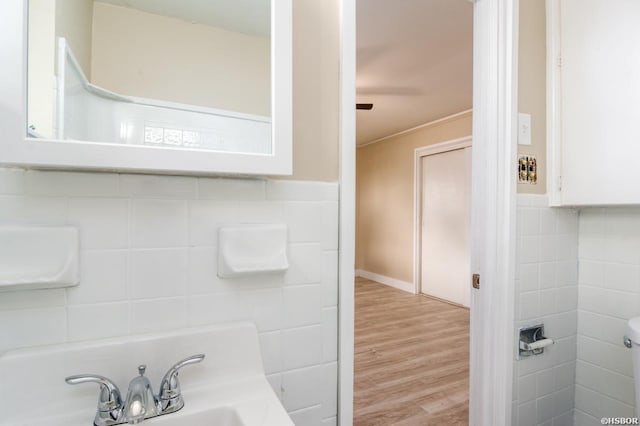 bathroom featuring a sink, tile walls, and wood finished floors