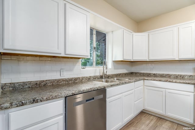 kitchen featuring a sink, backsplash, white cabinets, and stainless steel dishwasher