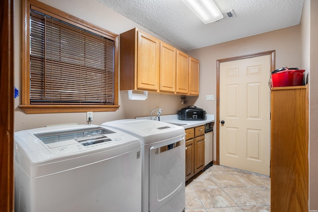 clothes washing area with visible vents, cabinet space, a sink, a textured ceiling, and independent washer and dryer