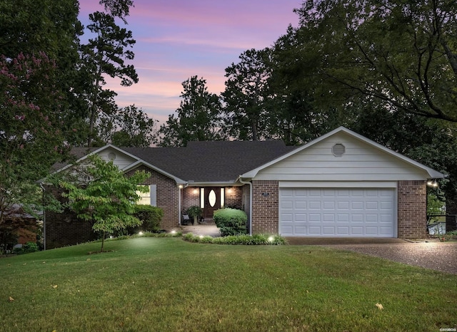 single story home with gravel driveway, brick siding, an attached garage, and a front lawn