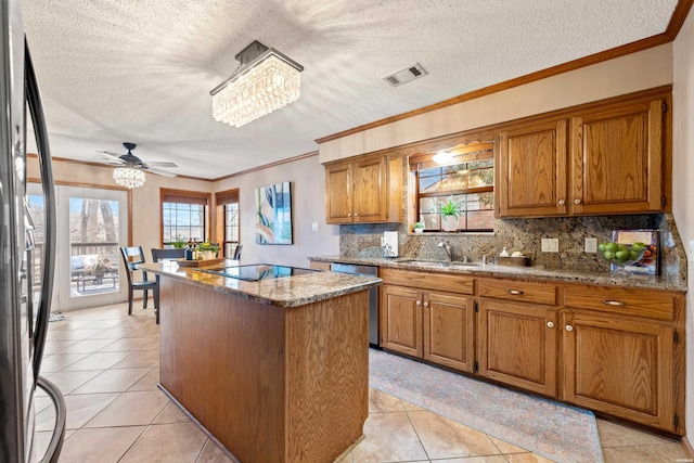 kitchen with a sink, a kitchen island, visible vents, appliances with stainless steel finishes, and brown cabinets