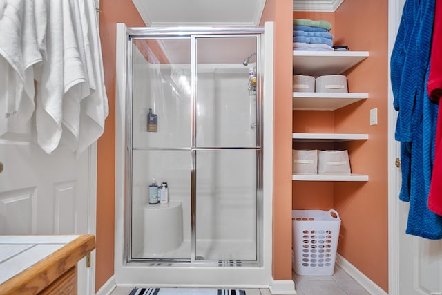 bathroom with baseboards, ornamental molding, a shower stall, and tile patterned floors