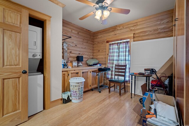 office with ceiling fan, stacked washer / dryer, rustic walls, and light wood-style flooring