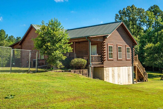 view of property exterior featuring a lawn, stairway, fence, metal roof, and log siding