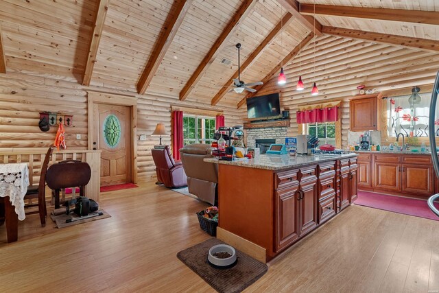 kitchen with high vaulted ceiling, light stone counters, a sink, open floor plan, and a center island