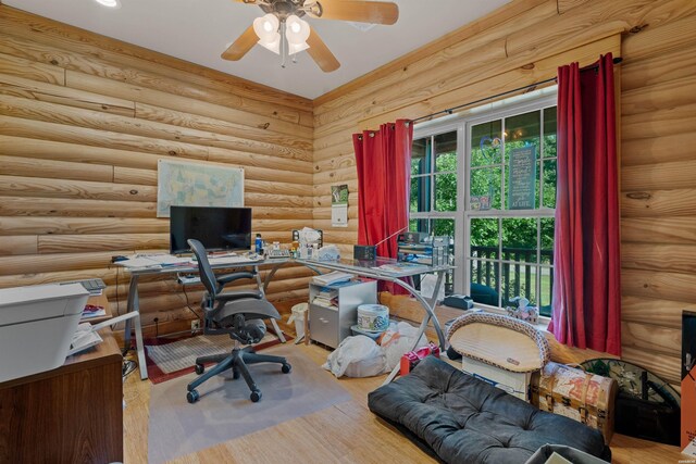 office space featuring rustic walls, a ceiling fan, and light wood-style floors