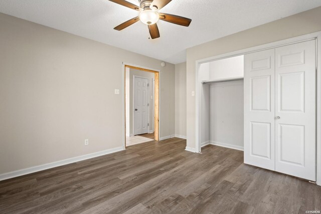 unfurnished bedroom with a closet, dark wood finished floors, baseboards, and ceiling fan