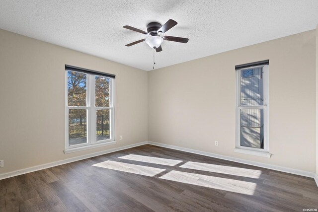 empty room featuring a textured ceiling, dark wood-style flooring, a ceiling fan, and baseboards