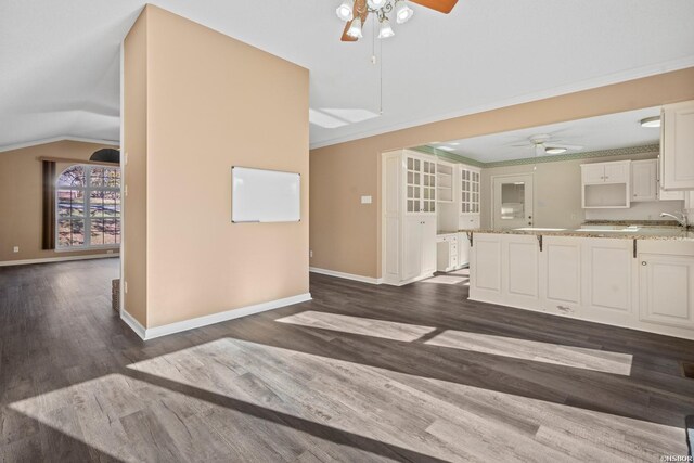 interior space featuring ceiling fan, light stone counters, white cabinets, open floor plan, and crown molding