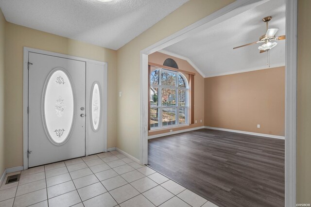 entrance foyer with visible vents, vaulted ceiling, a textured ceiling, and baseboards