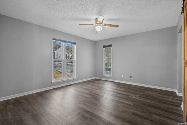 empty room with a ceiling fan, dark wood finished floors, a textured ceiling, and baseboards