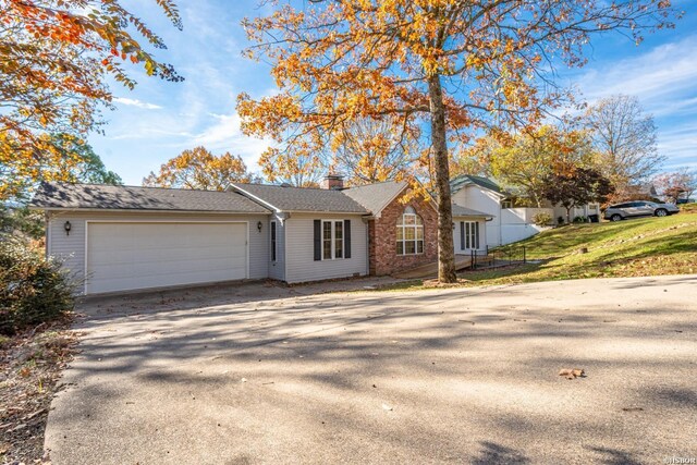 single story home featuring a garage, driveway, a chimney, and a front yard