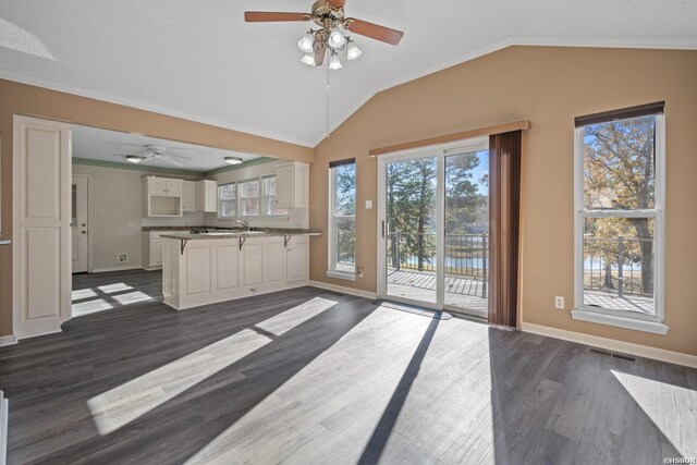 kitchen with dark wood-style flooring, white cabinets, vaulted ceiling, and baseboards