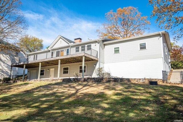 rear view of property with a deck, a yard, a chimney, and fence