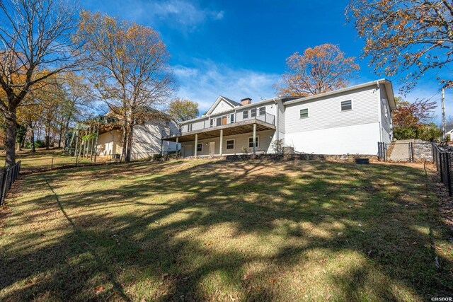 back of property featuring a deck, a lawn, a chimney, and a fenced backyard