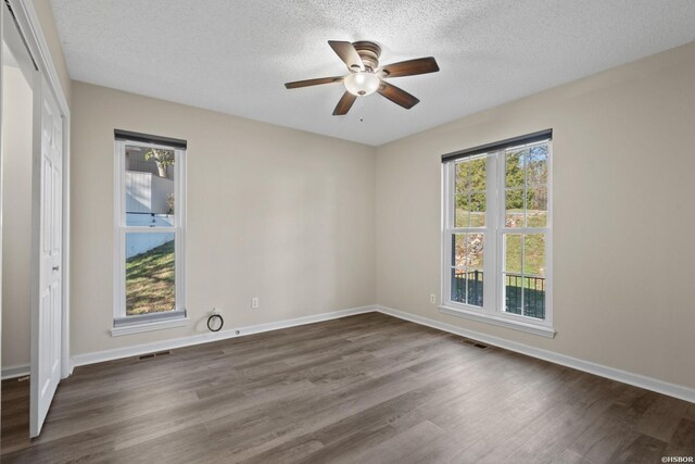 spare room with dark wood-style floors, plenty of natural light, and baseboards