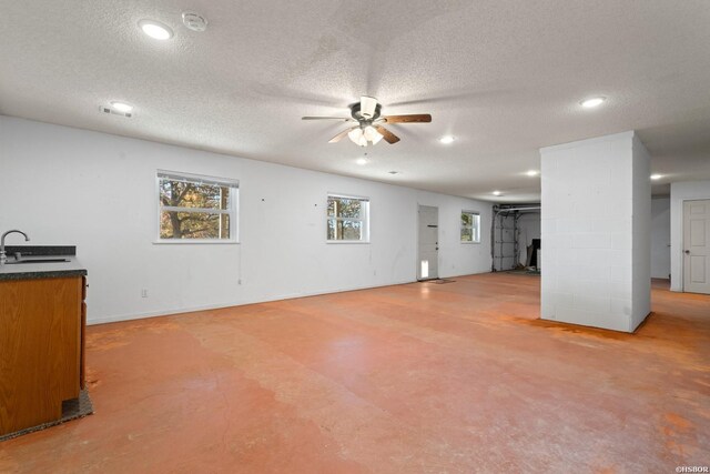 unfurnished living room featuring ceiling fan, a textured ceiling, concrete floors, a sink, and recessed lighting