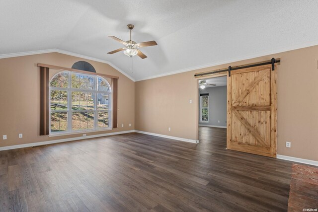 spare room with a barn door, dark wood finished floors, vaulted ceiling, and a wealth of natural light