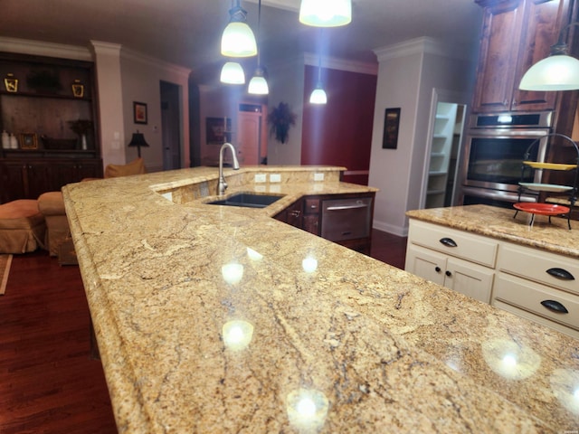 kitchen with dark wood-type flooring, decorative light fixtures, ornamental molding, light stone counters, and a sink