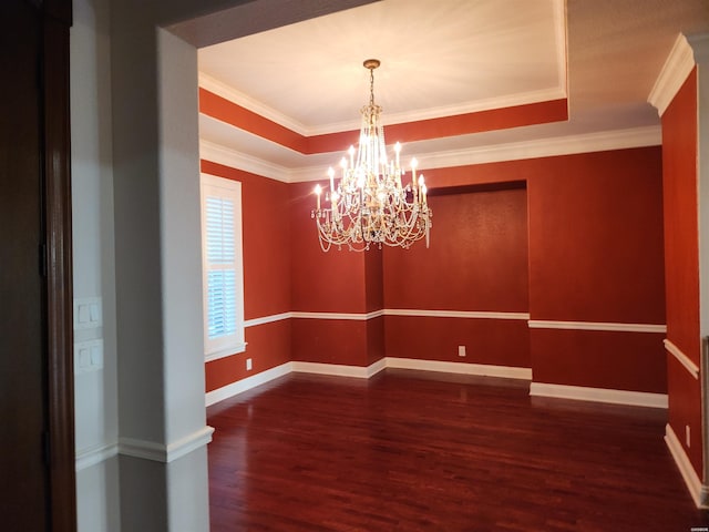 empty room featuring a tray ceiling, baseboards, wood finished floors, and crown molding