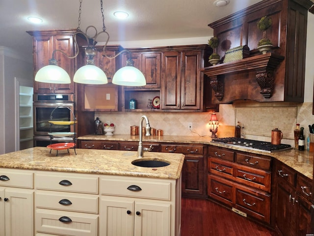 kitchen with a sink, tasteful backsplash, cream cabinets, gas stovetop, and double oven