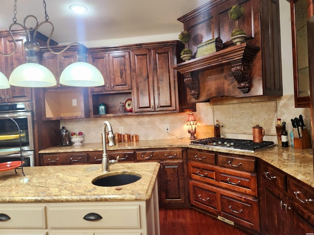 kitchen with tasteful backsplash, appliances with stainless steel finishes, light stone counters, and a sink