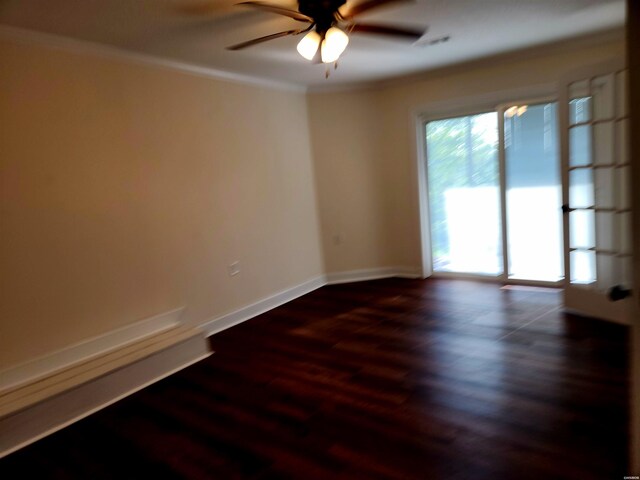 spare room with dark wood finished floors, a ceiling fan, baseboards, and ornamental molding