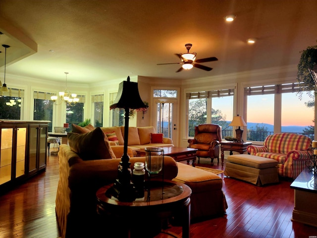 living room featuring dark wood-style floors, crown molding, and ceiling fan with notable chandelier