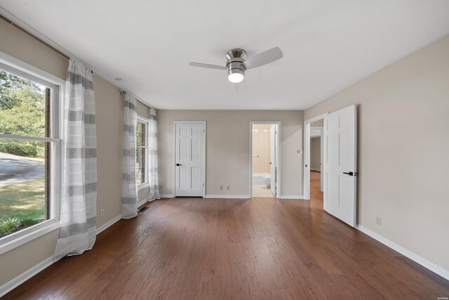 unfurnished room with a healthy amount of sunlight, baseboards, and dark wood-type flooring