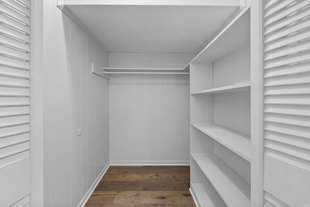 walk in closet with dark wood-style floors