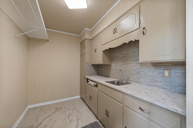 kitchen featuring tasteful backsplash, light stone counters, marble finish floor, crown molding, and a sink