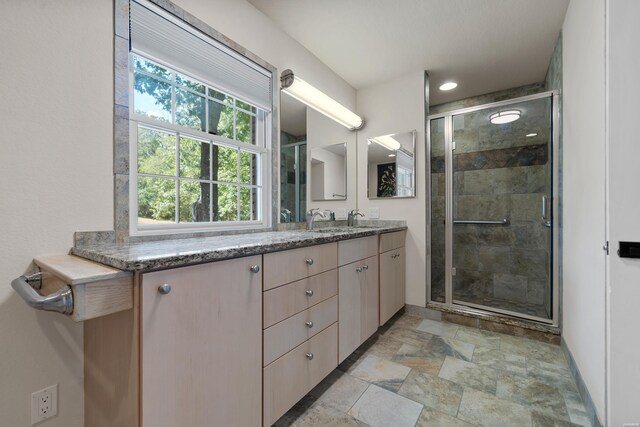 full bathroom with stone finish flooring, baseboards, vanity, and a shower stall