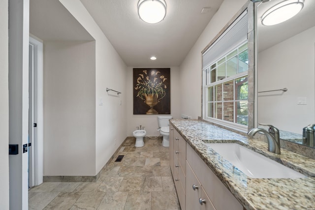 bathroom featuring visible vents, baseboards, toilet, vanity, and a bidet