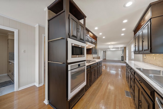 kitchen with stainless steel appliances, light wood finished floors, light countertops, and visible vents