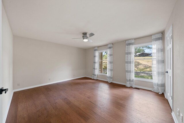 spare room with a ceiling fan, dark wood finished floors, and baseboards