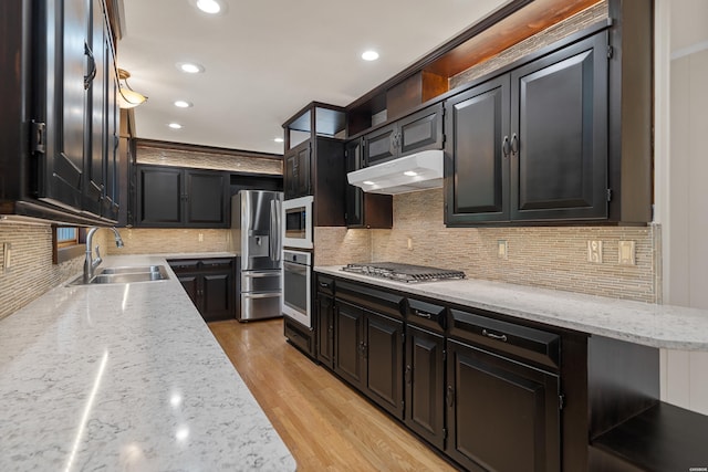 kitchen with light stone countertops, a sink, under cabinet range hood, and open shelves