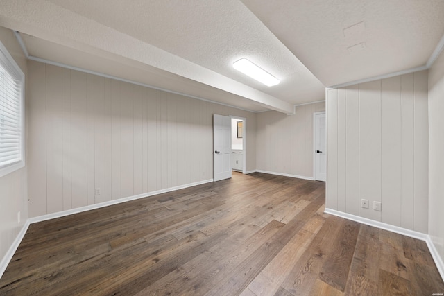 basement featuring a textured ceiling, baseboards, wood finished floors, and ornamental molding